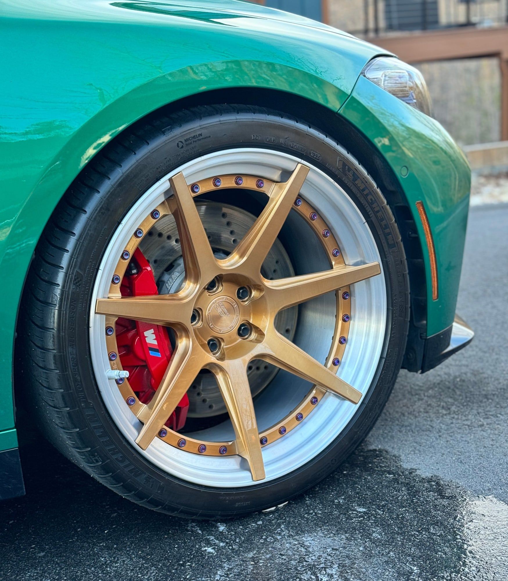 Green sports car with gold wheels and red calipers, paint polished to a high gloss
