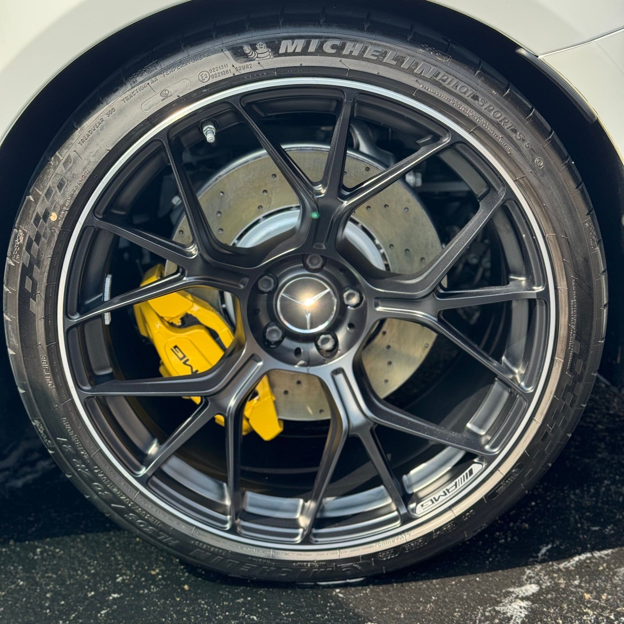Close-up of a cleaned black wheel with a yellow brake caliper and Michelin tire