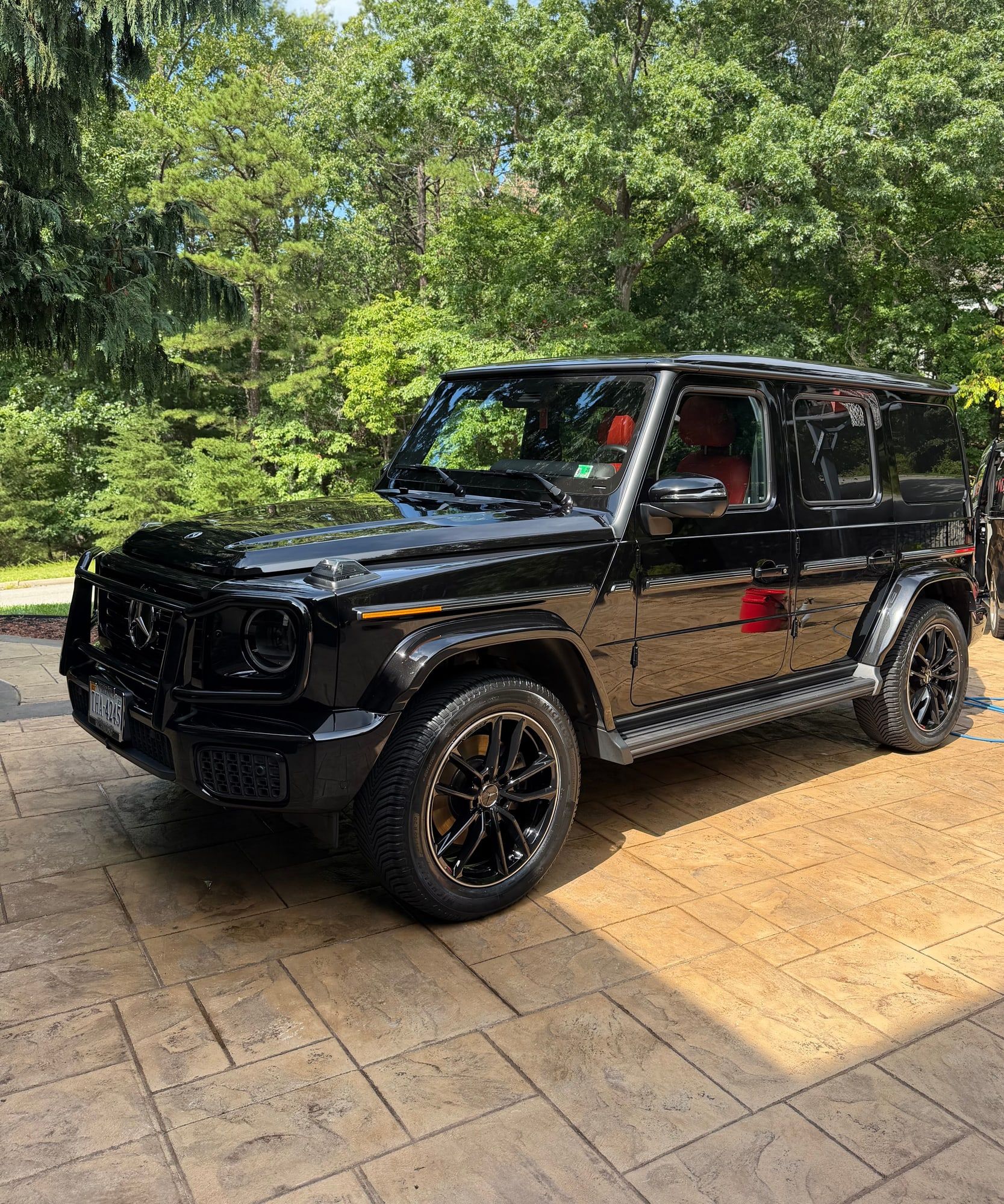 Freshly detailed black Mercedes G-Wagon parked on a stamped-concrete driveway